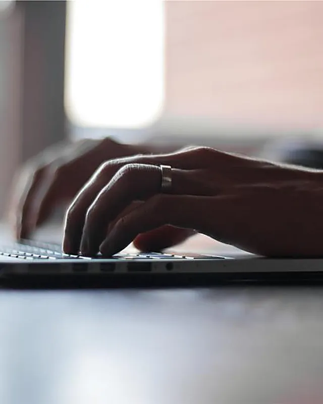 Hands typing at a keyboard late in the day