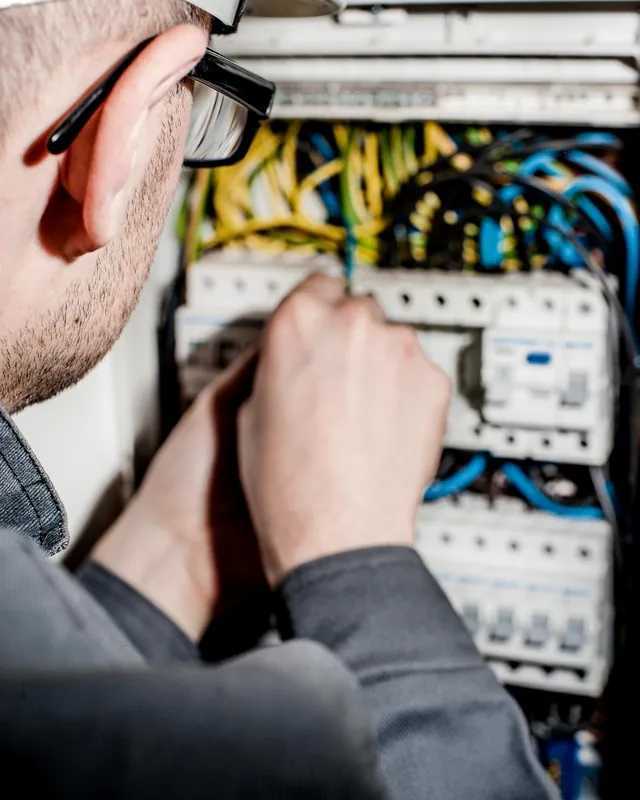 An electrician working inside a distribution panel