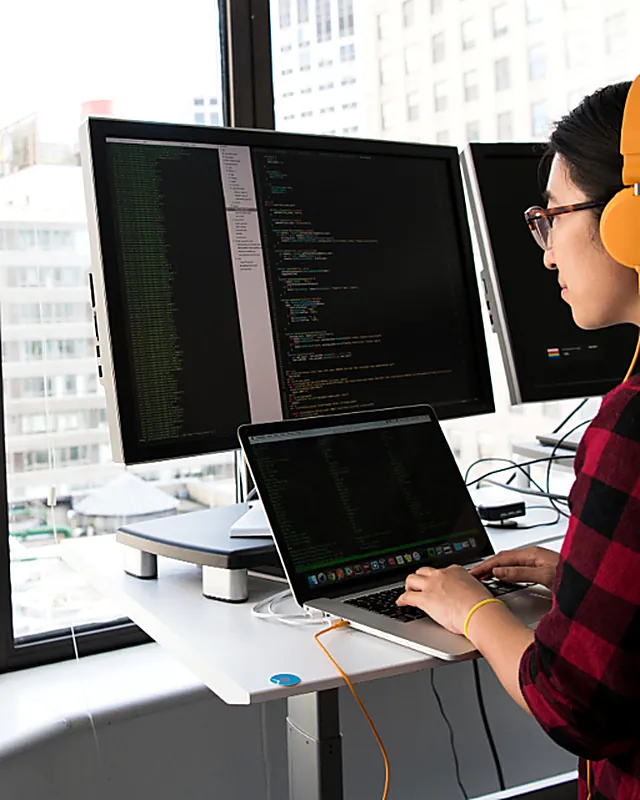 A developer at a multiple monitor workstation reviewing code