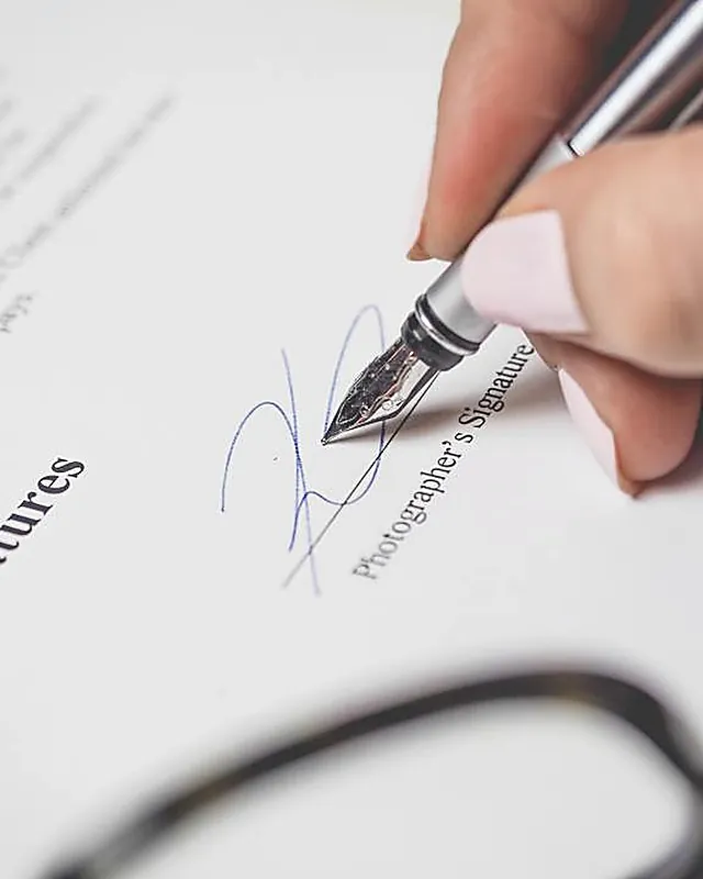 A hand signing a formal document