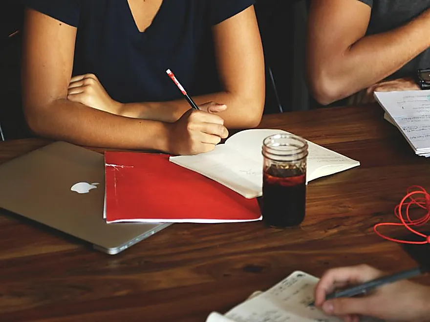 Two people talking through paperwork across a table